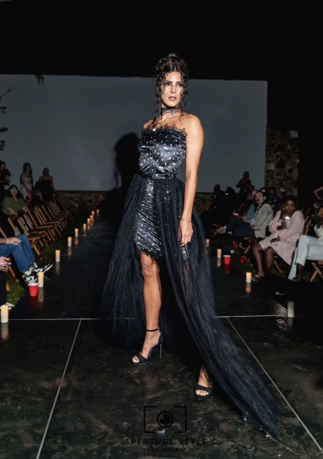 A model in a black gown on the candle-lit runway at Sekrit Theater during Luxe in Love