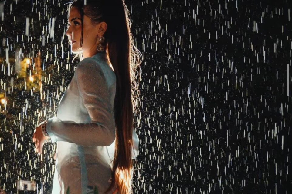 A model in a white gown stands under falling rain on stage at Sekrit Theater during Luxe in Love
